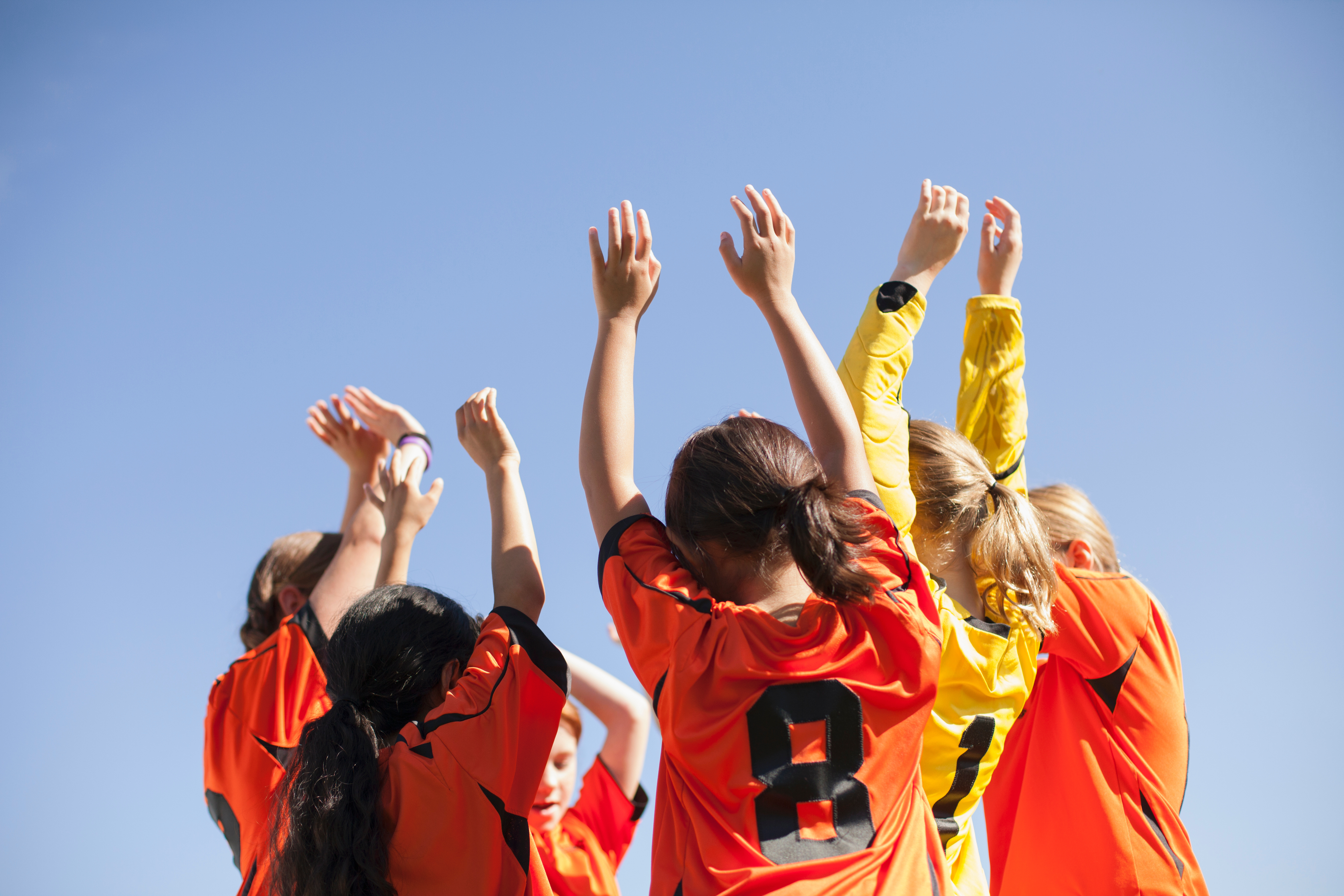 Soccer girls with arms raised in a cheer.